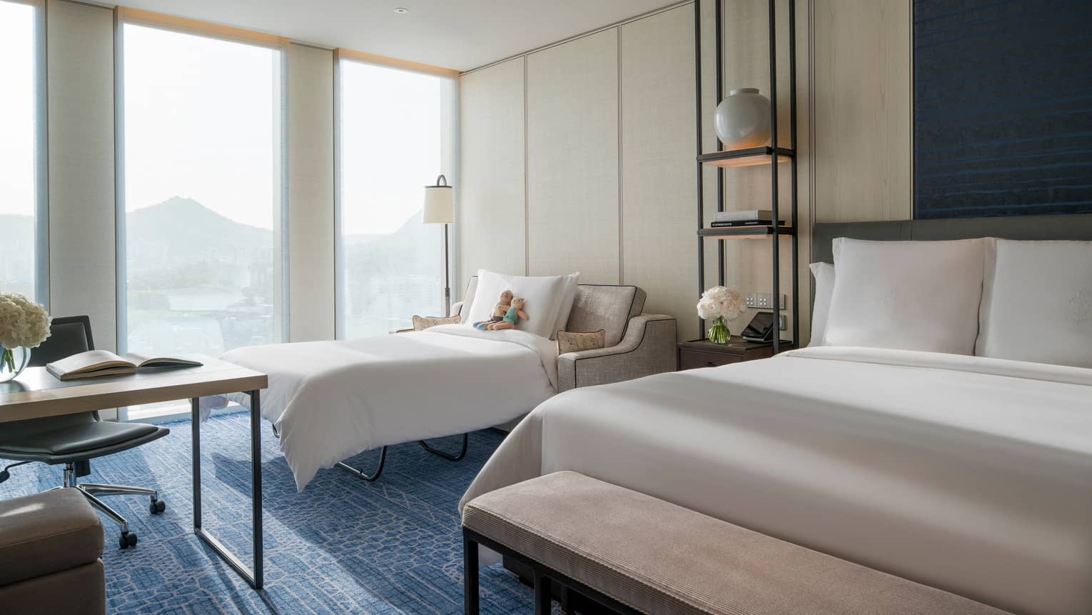 Premier Family Room pull-out sofa with stuffed animals by hotel window between work desk, bed