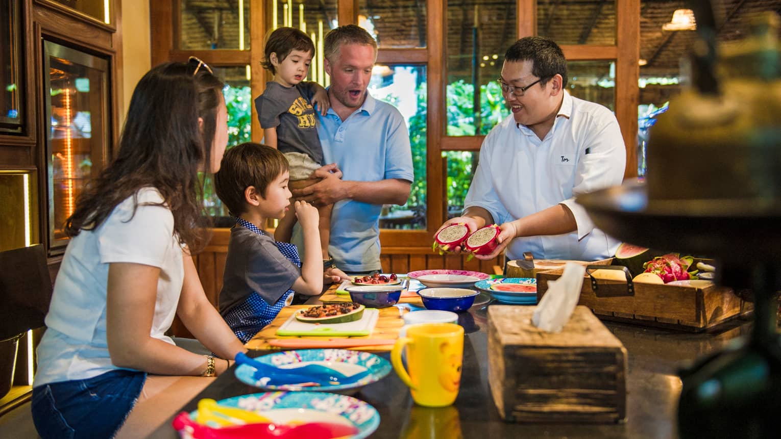 Chef presents two halves of dragon fruit to family during Thai cooking demonstration