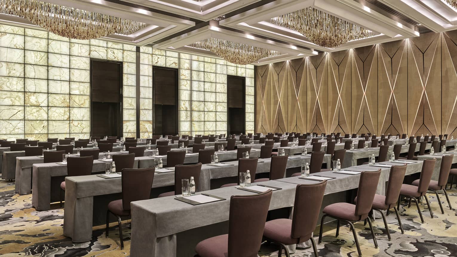 Brightly lit meeting room set up classroom style with rows of burgundy chairs