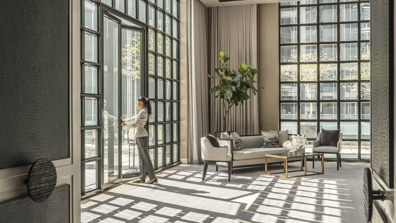 Studio II with cream-coloured carpet and matching furniture, green potted foliage, sunlight streaming in through floor-to-ceiling windows