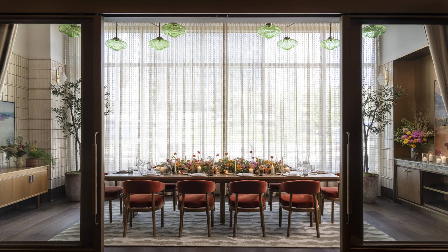 Contemporary private dining room with green glass pendant lights and red velvet chairs