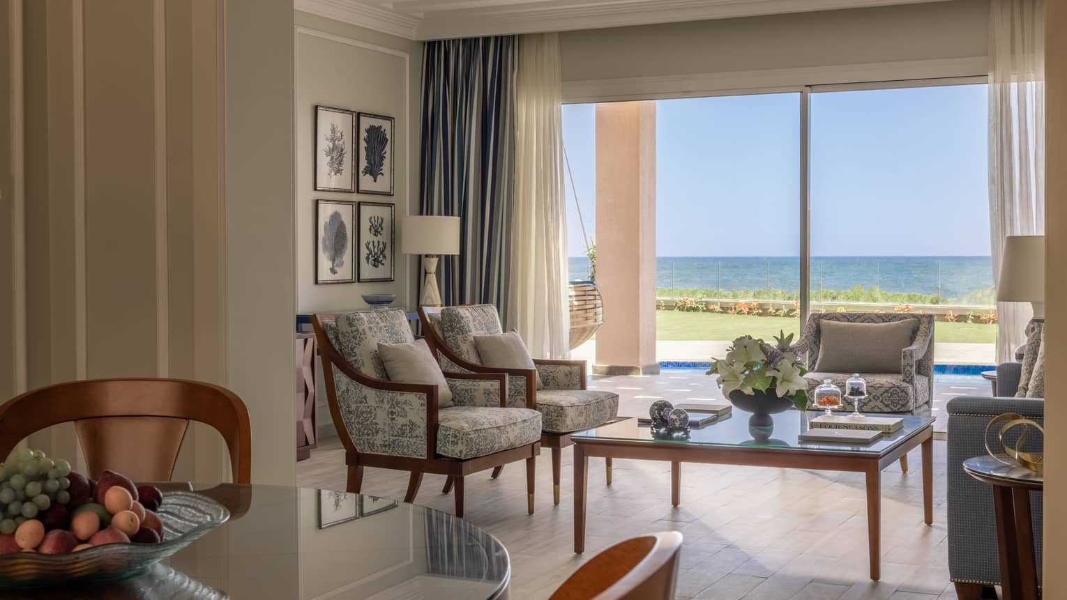 Two-Bedroom Beach Villa living area with three armchairs, blue sofa, glass coffee table, sliding glass door to terrace