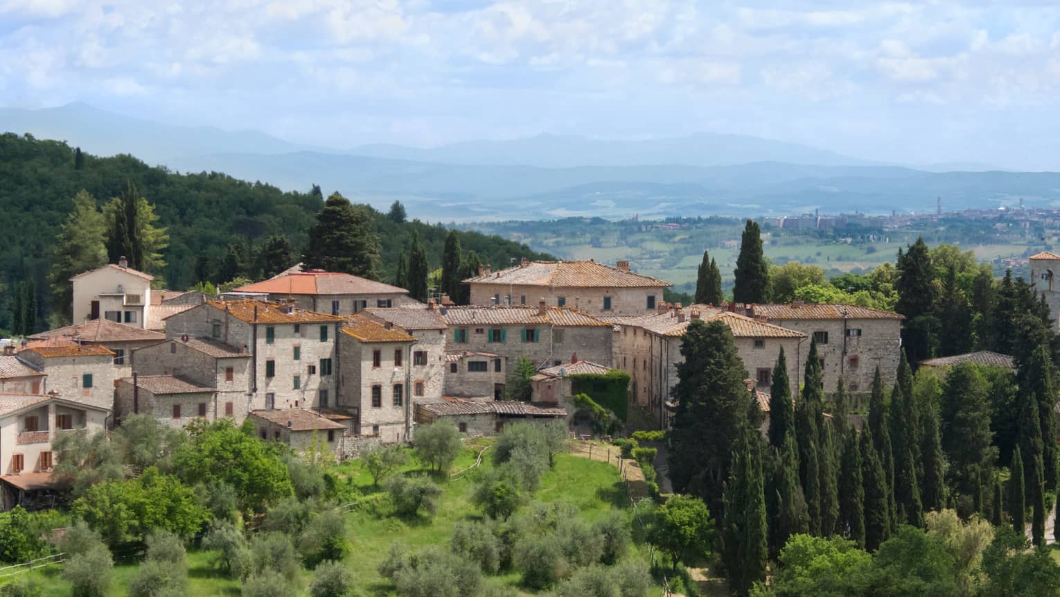 Tuscan countryside with historic stone building against rolling green hills