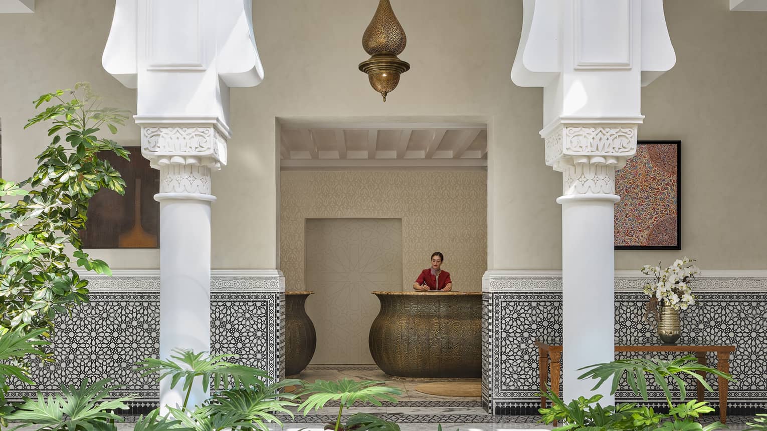 Four Seasons Hotel Rabat reception counter, viewed through an open-air courtyard with greenery and ornate stone columns