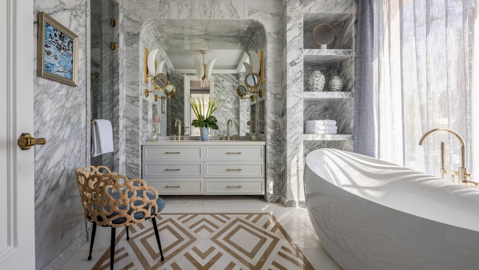 The Palace bathroom with large soaking tub, marble walls, double vanity, built-in shelves