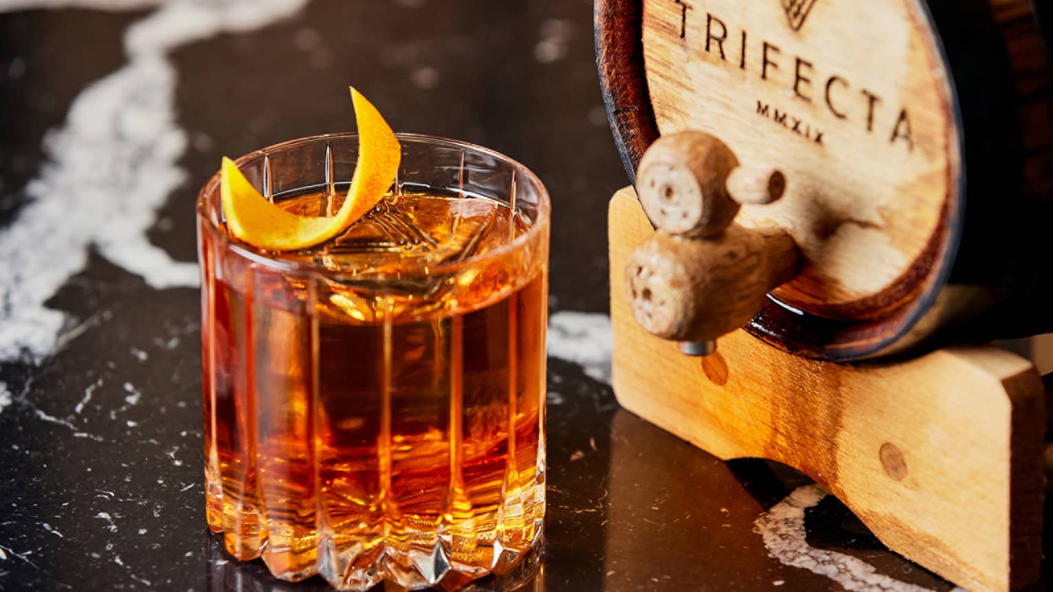 An amber coloured cocktail with an orange peel garnish.