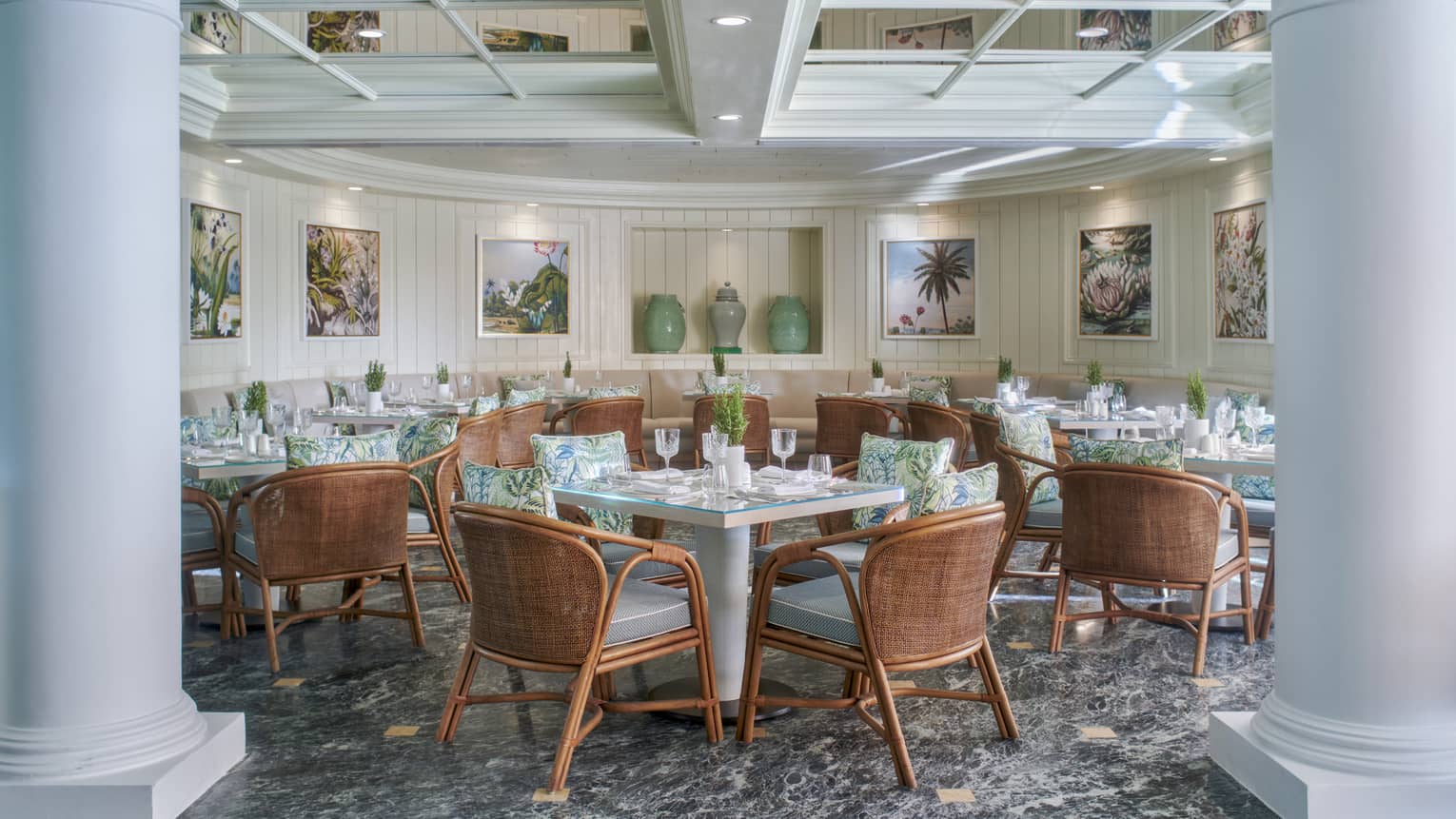 Byblos indoor dining space with rattan chairs and square tables, light blue colour scheme, granite flooring, white columns