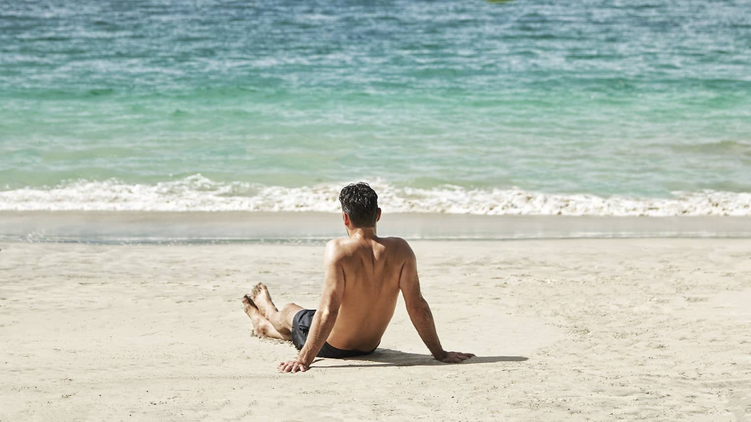 Man relaxes on beach looking out over the sea