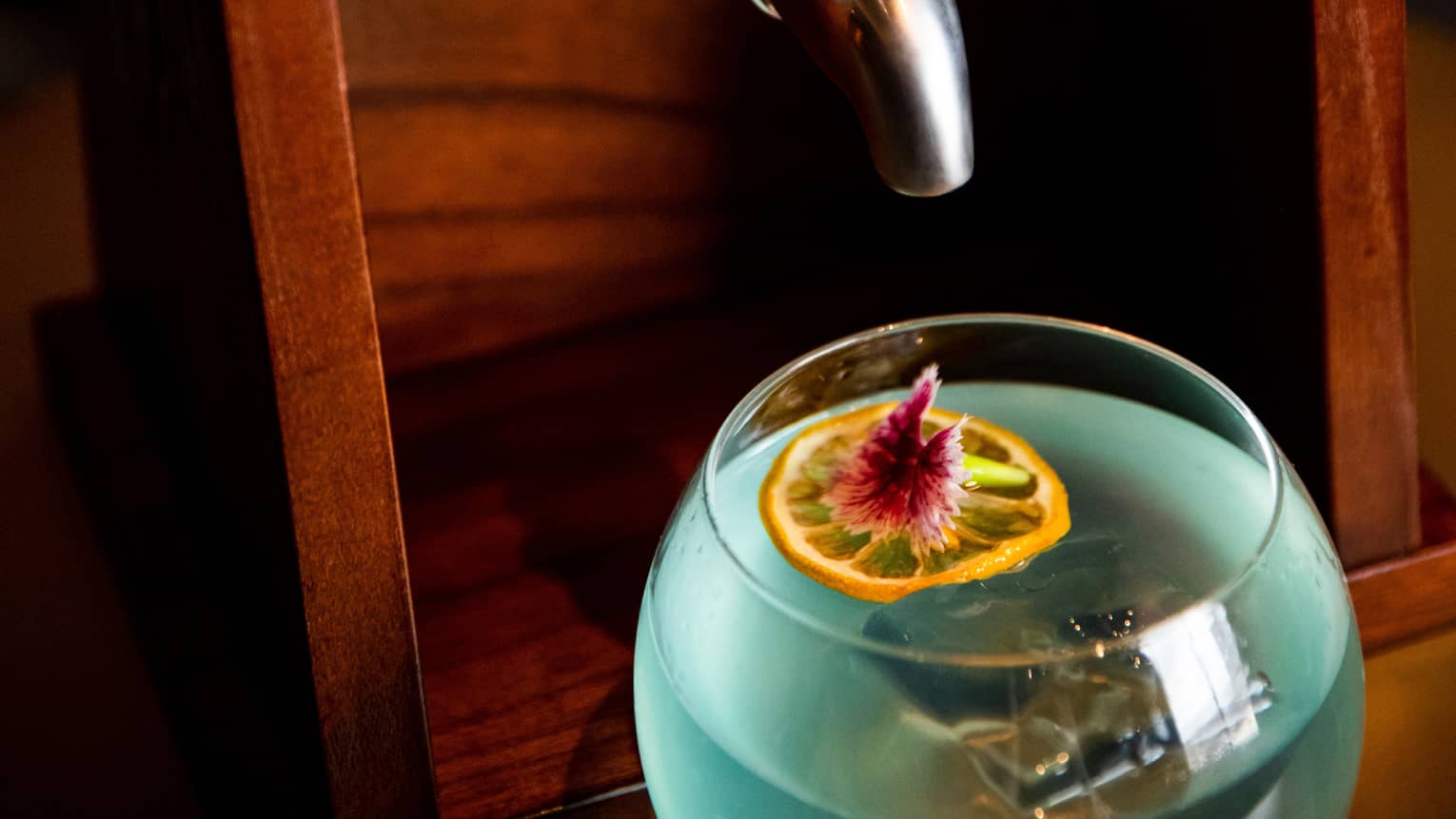 A blue cocktail with a ship in a bottle above it.