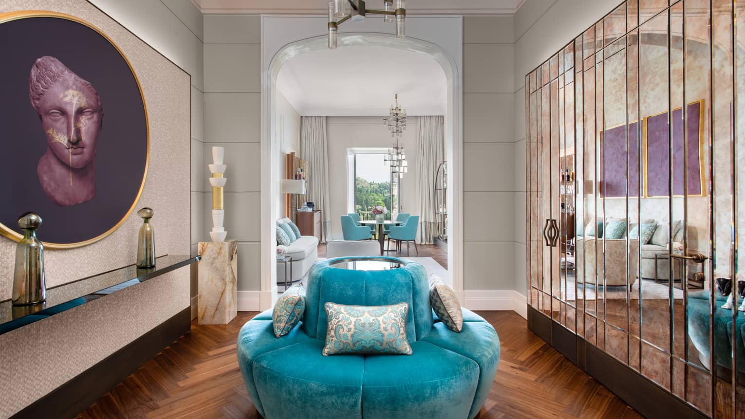 Room with turquoise, circular sofa, mirrored wall of closets, artwork