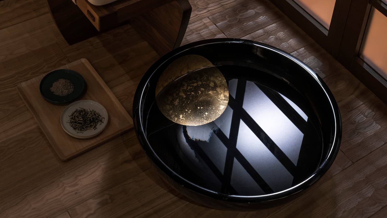 Light reflected in black bowl with water in spa