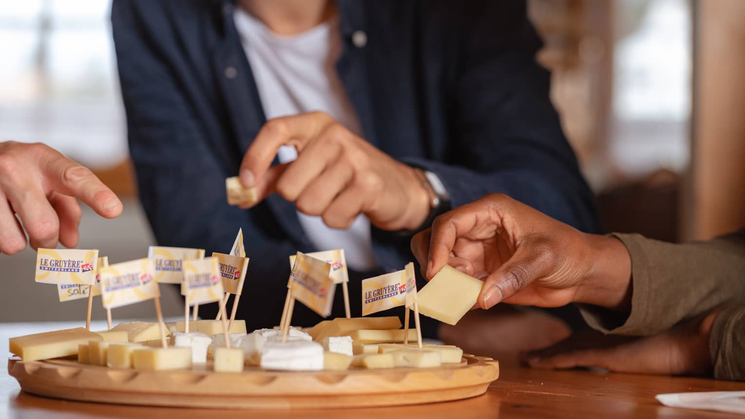 Three friends taking cheese samples from cheese board