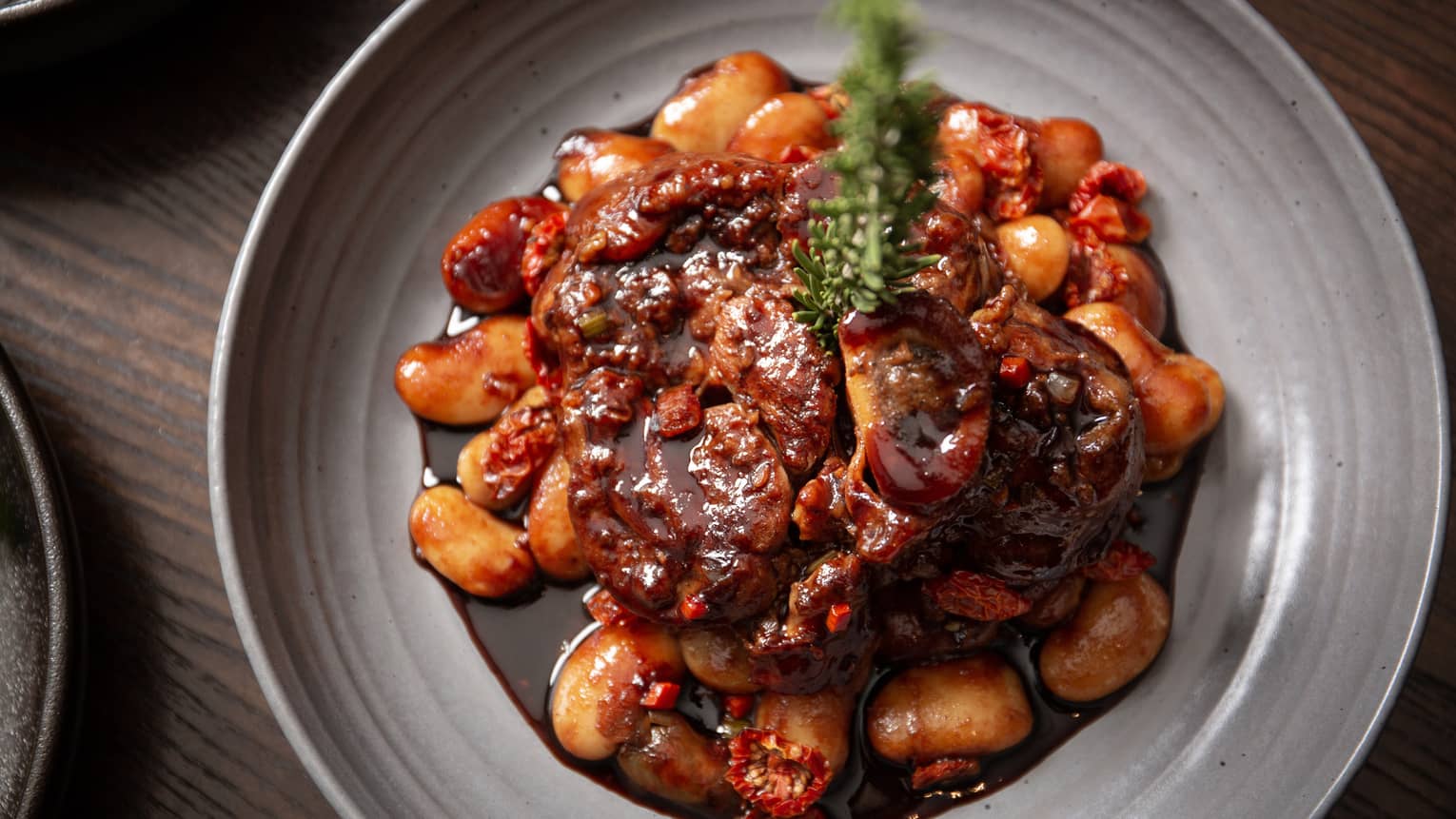 Veal in a dark red sauce on a grey plate.