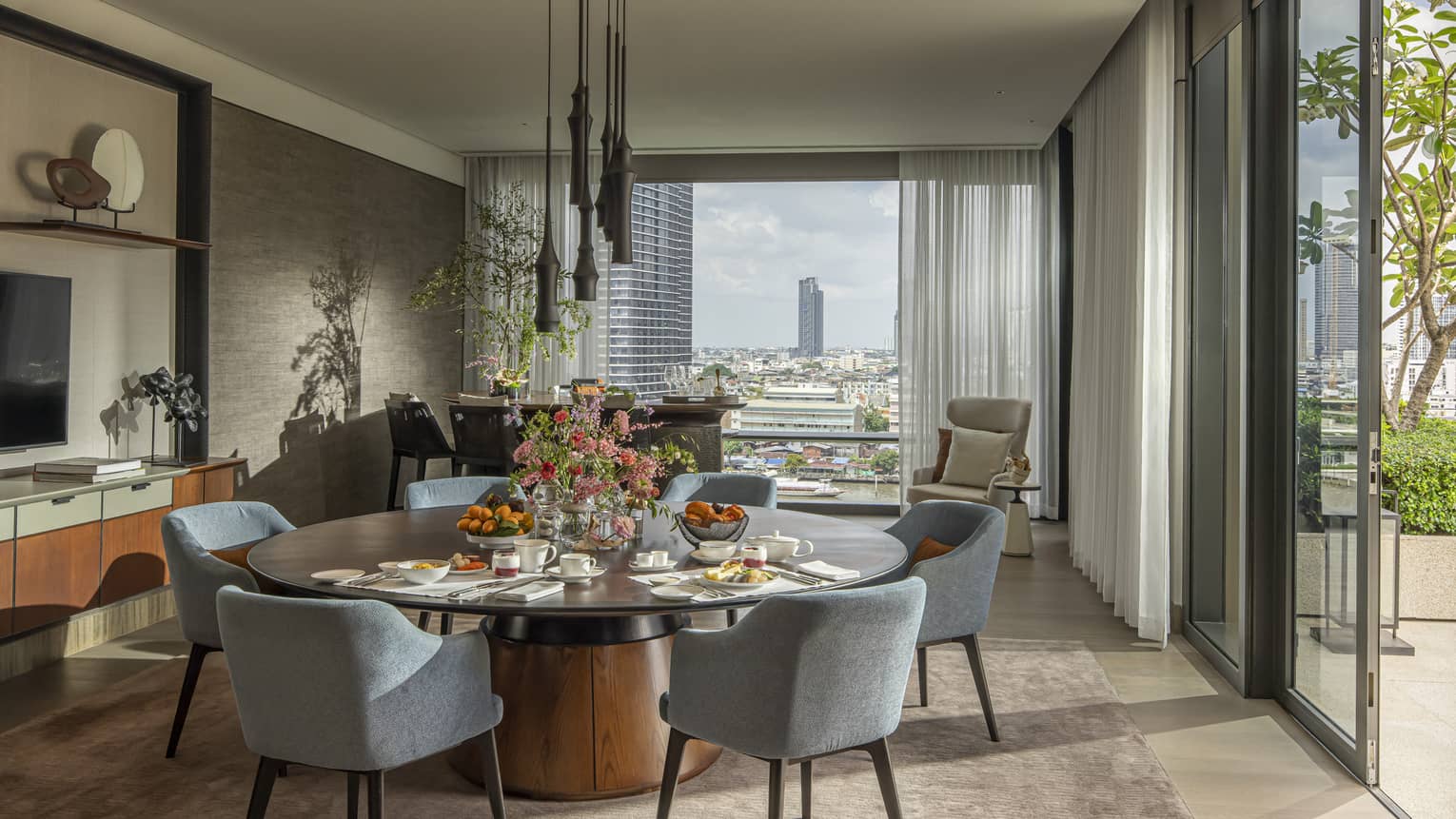 Hotel suite with large round dining table and views of Bangkok