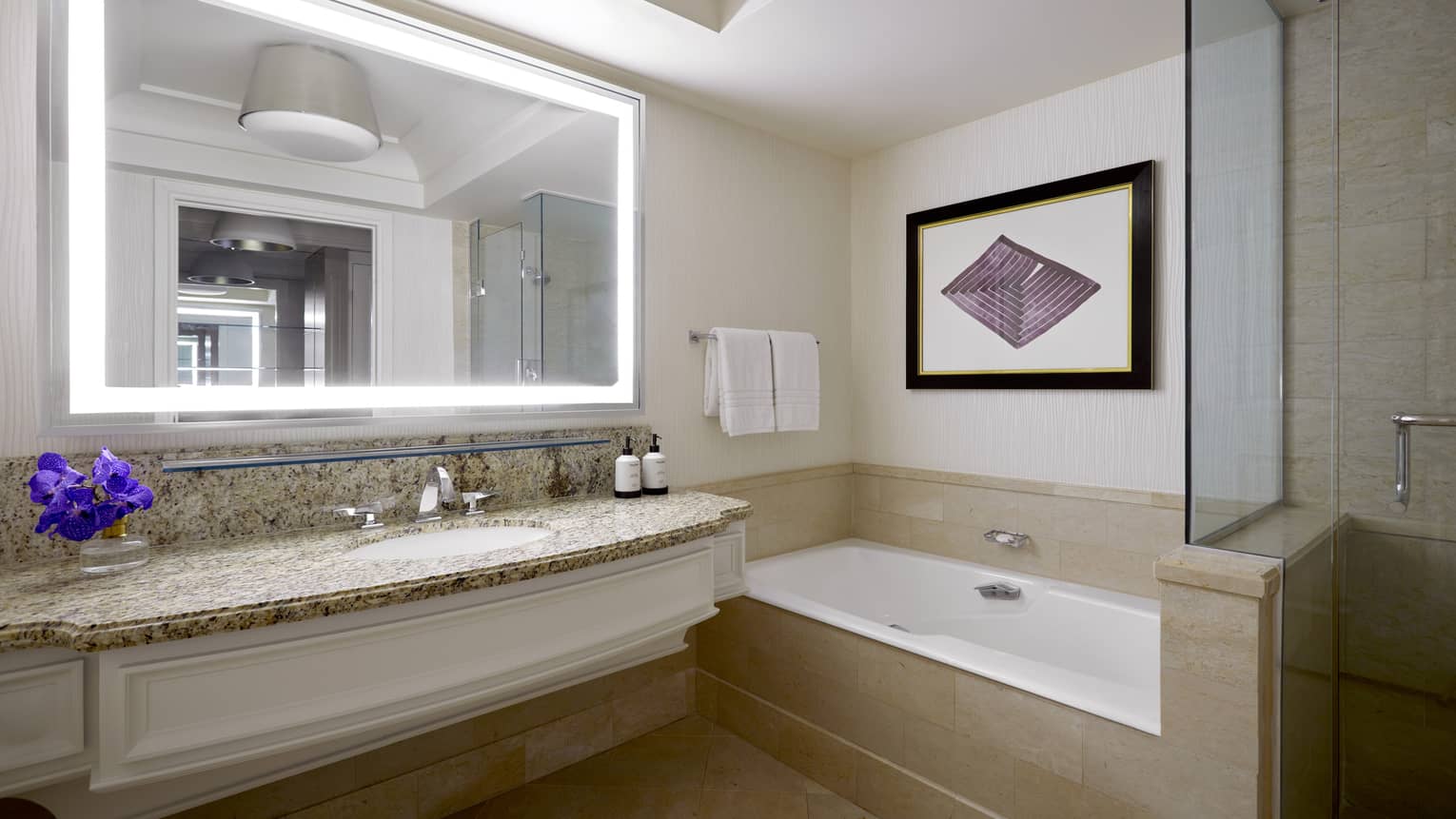 Bathroom with tub, sink and large mirror.