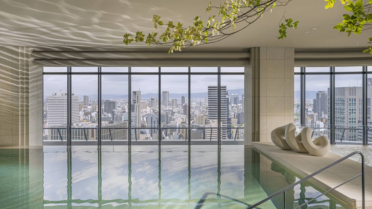 Indoor pool at Four Seasons Hotel Osaka, with wall of windows looking out to Osaka city