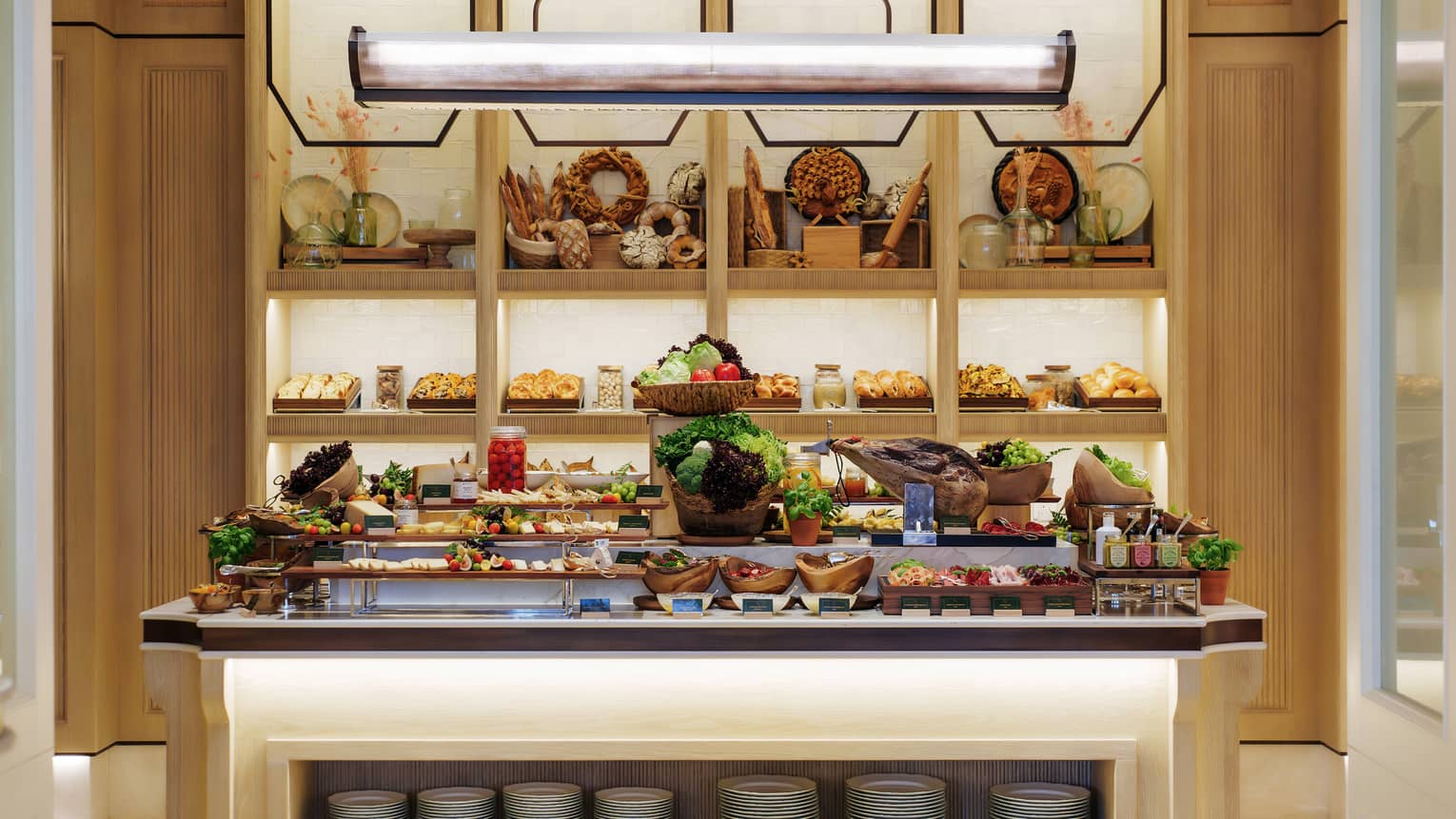 Breakfast buffet display on a large centre island with shelves of break and baked goods in the background