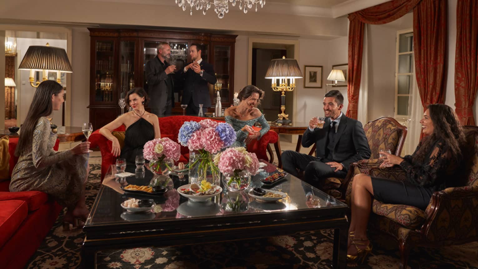 People mingle in an elegant living room with crystal chandelier