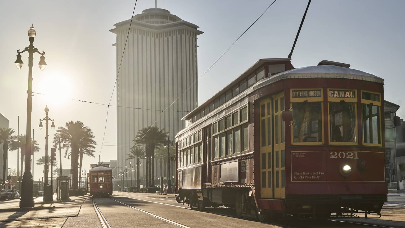 A trolly on a brightly lit road during day.