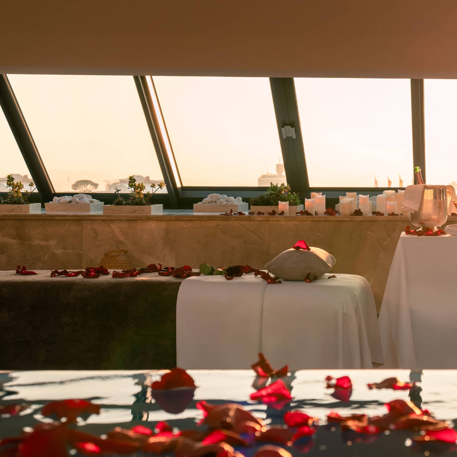 Spa pool sprinkled with red rose petals and couples spa tables poolside with skylight views