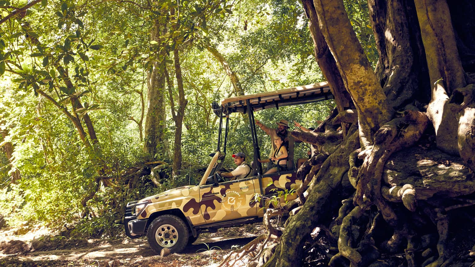 A tour guide and two guests explore the Costa Rican jungle in an open-air Jeep