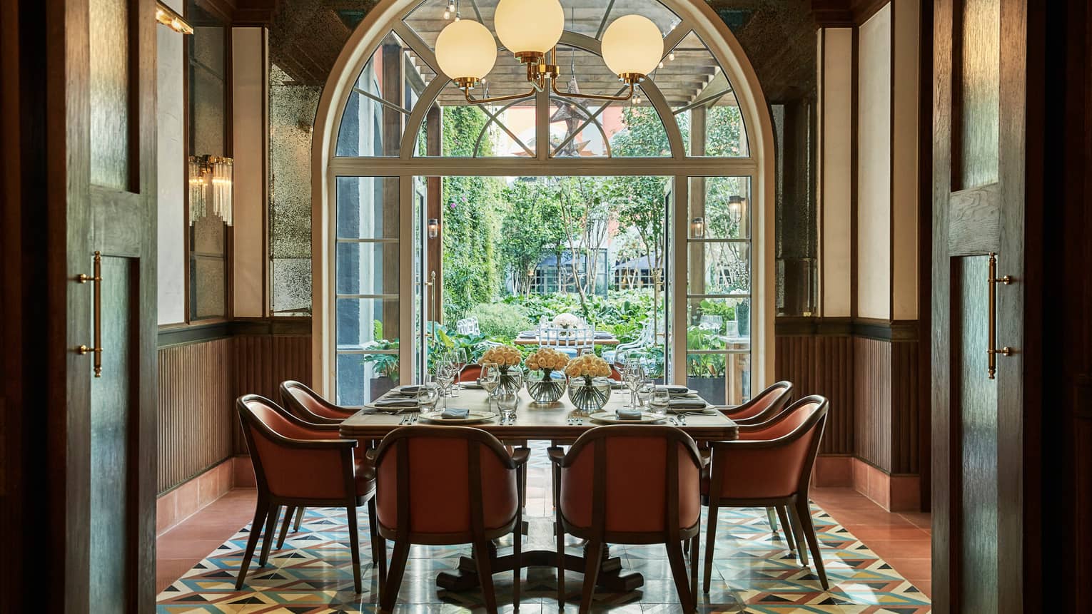 Private dining table under sunny arched window, globe lights