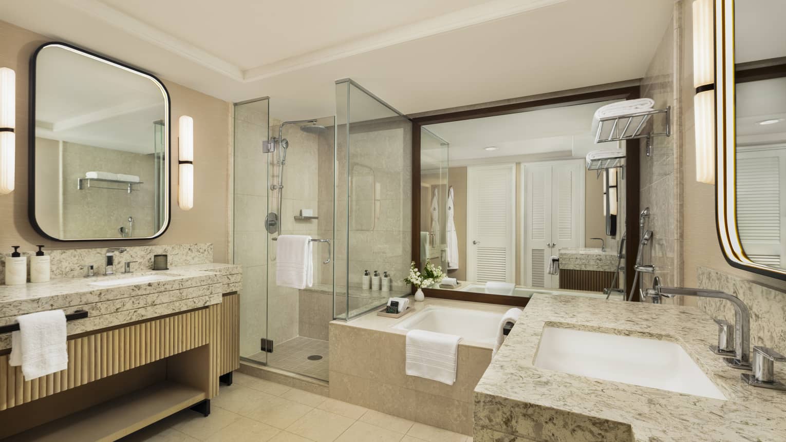Hotel room bathroom featuring sunken tub, separate glass shower and a sink vanity on each side of the bathroom