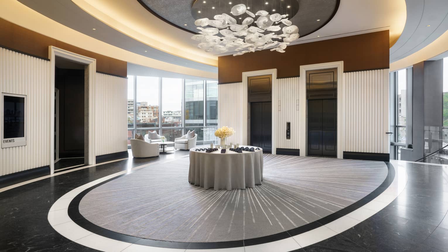 Lobby pre-function area with chandelier, uplighting, two elevators, view of Boston skyline
