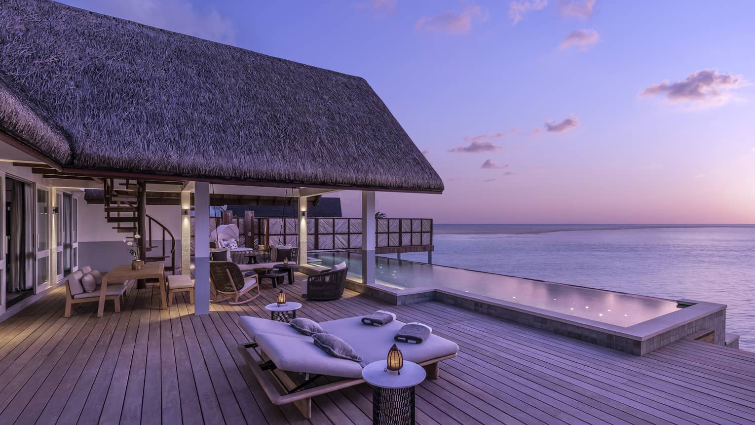 Luxurious overwater bungalow with an expansive wooden deck and infinity pool