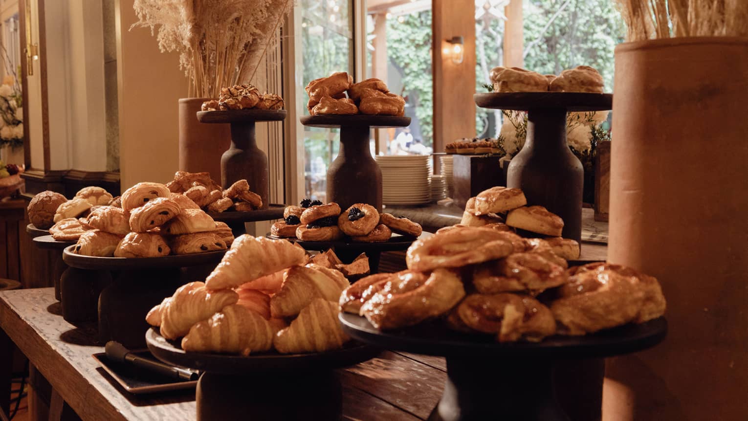 A table in an indoor dining space with platters of a variety pastries