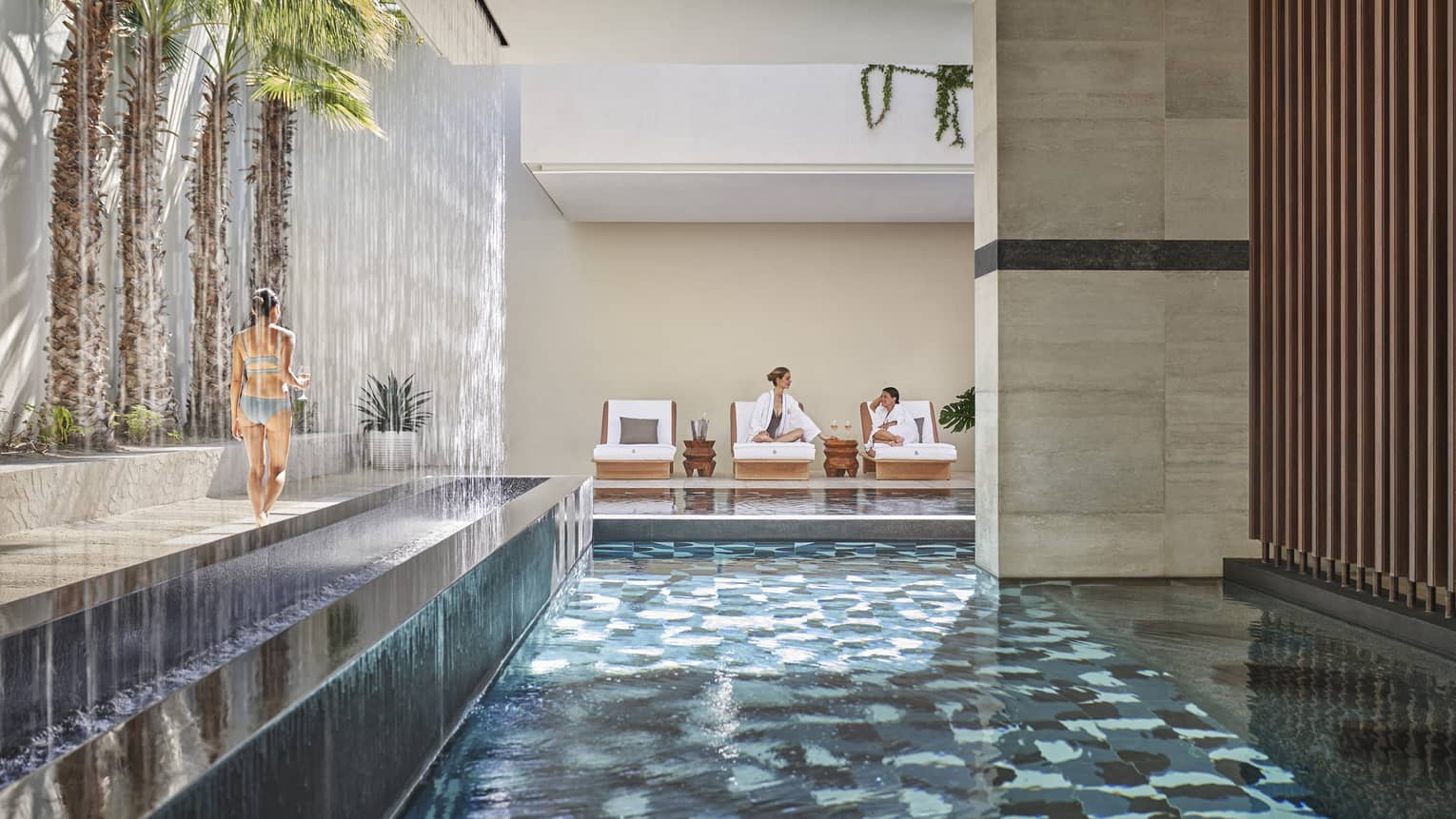 An indoor/outdoor spa area with a pool, palm trees, and lounge chairs.