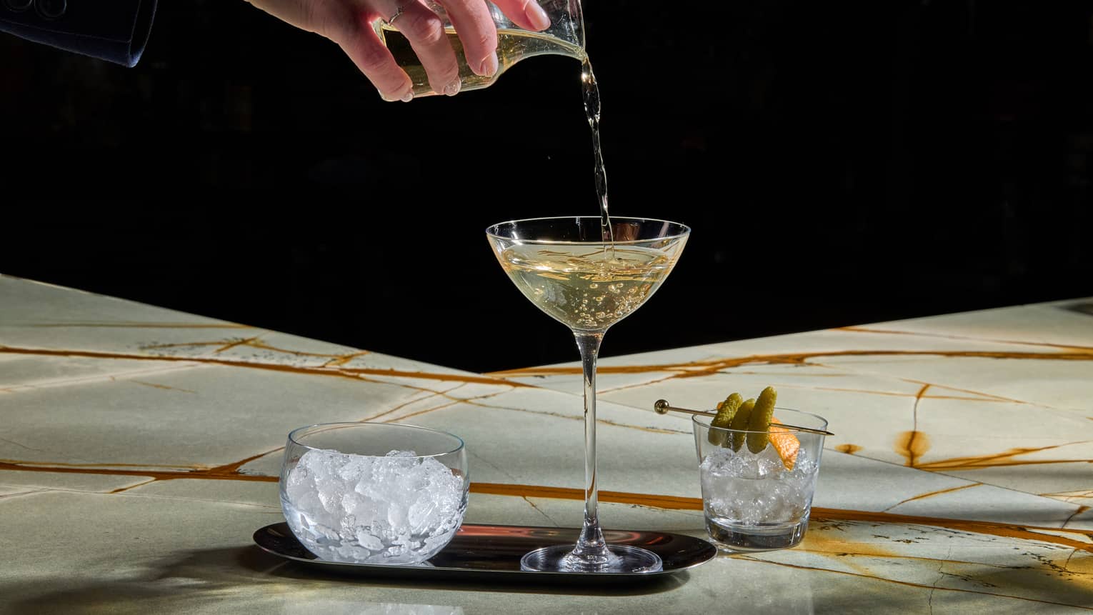 Hand pouring a beverage into a martini glass
