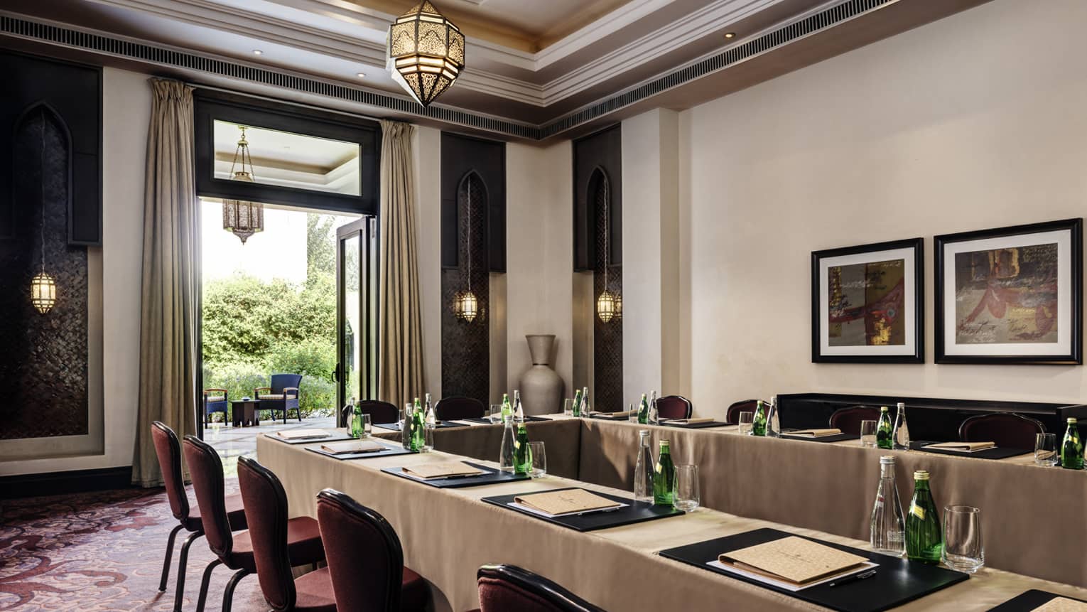 Long meeting tables, chairs under high ceiling, framed art by open patio door