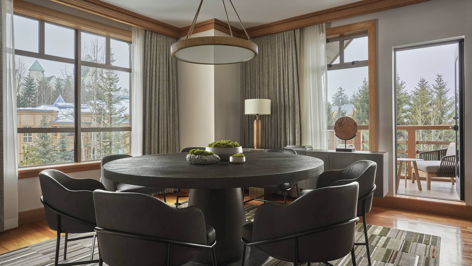Round dining table with six modern, leather seats and a door leading out to a balcony