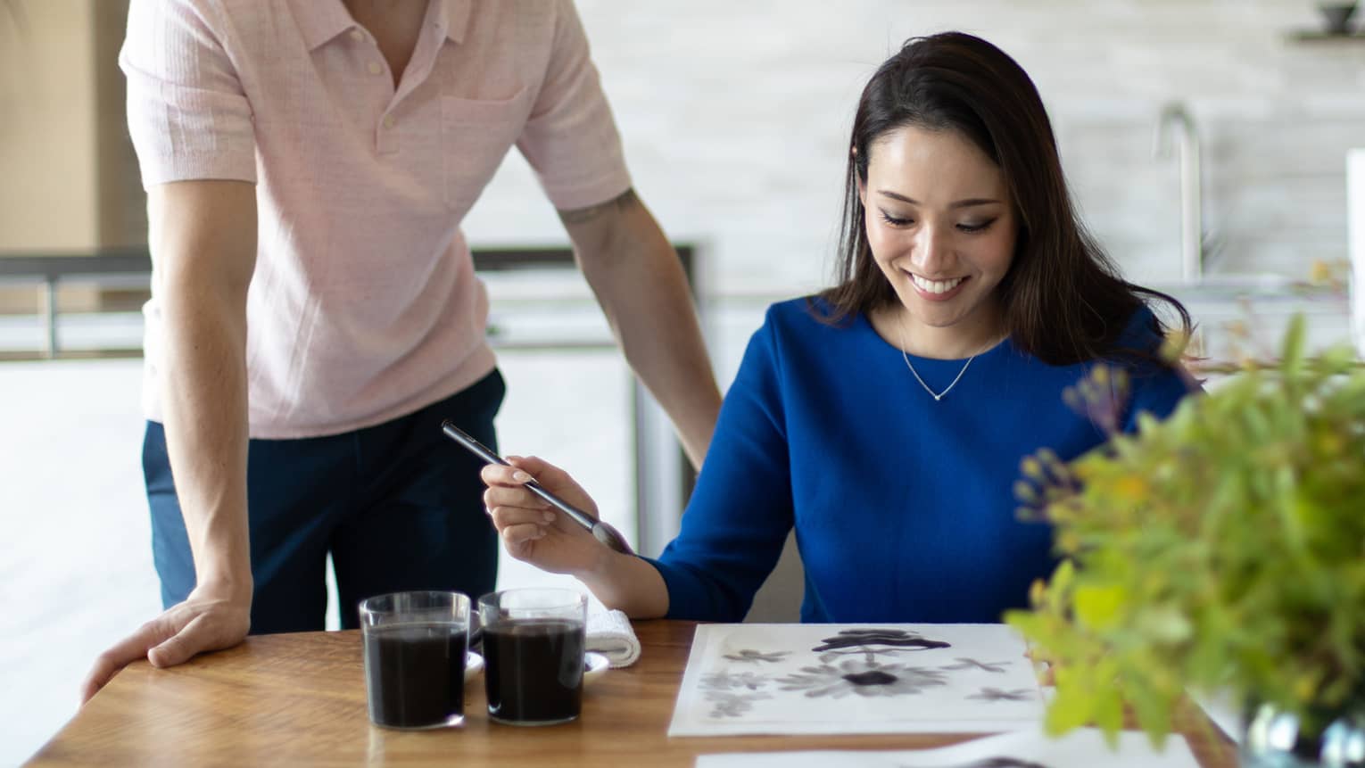 Person smiling while painting with watercolours at a table