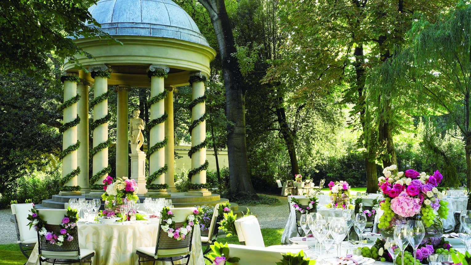 Garden reception, round, flower covered banquet tables by gazebo with white pillars