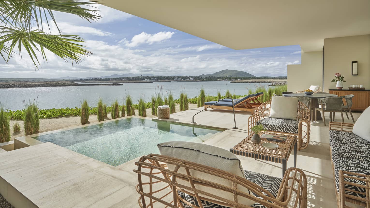 Modern terrace with seating vignette beside infinity pool, overlooking water 