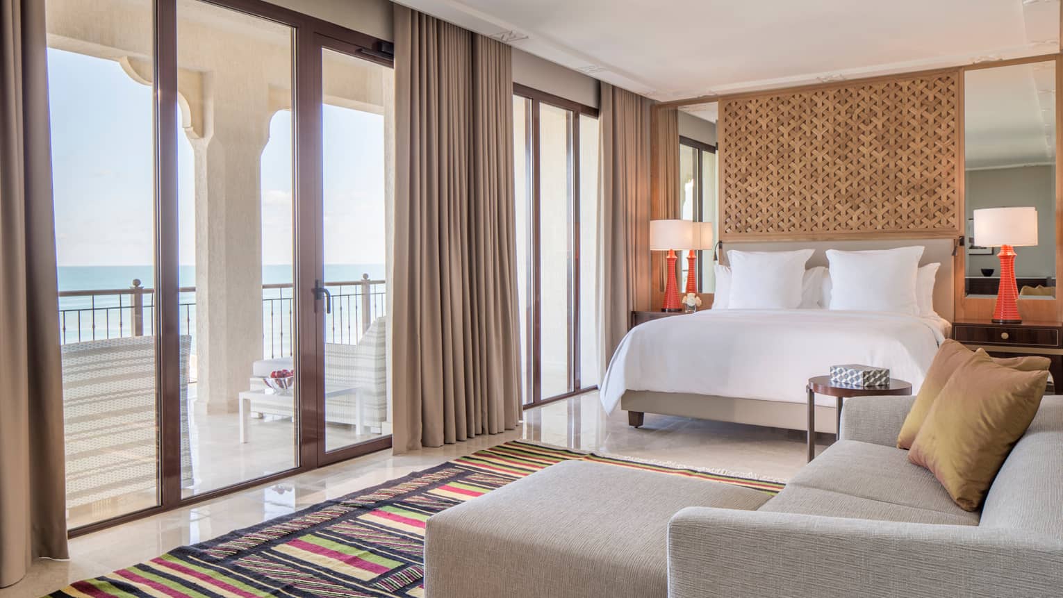 Premier Room bed, L-shaped sofa by floor-to-ceiling windows, balcony doors