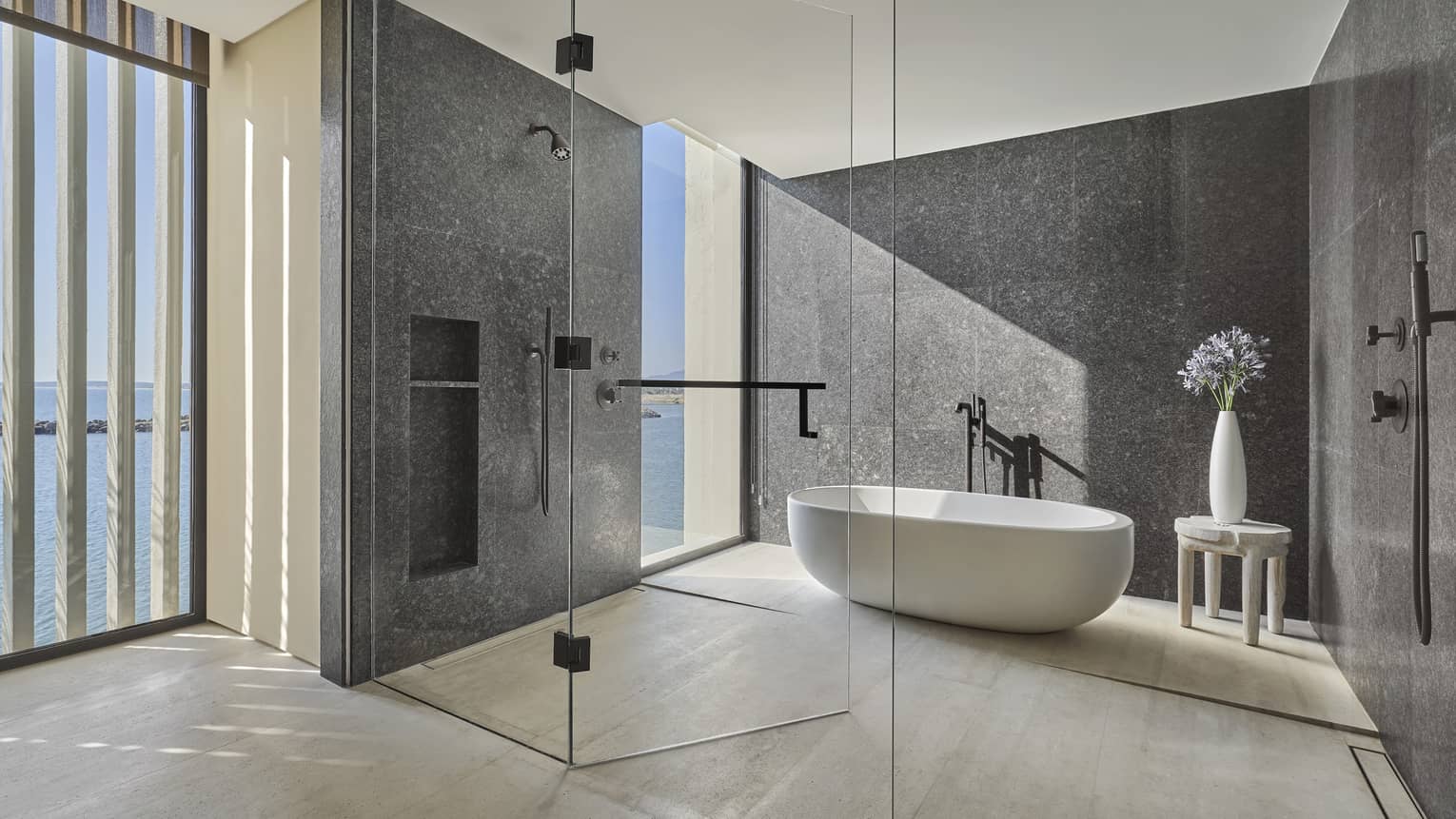 Two Bedroom Sunrise Suite bathroom with large soaking tub inside marble-walled glass shower area, floor-to-ceiling window