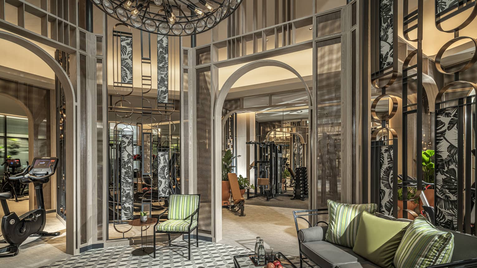 Fitness Centre lobby with high ceilings, round wrought-iron chandelier, sofa with green accent pillows