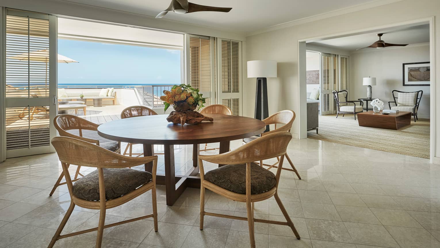 Residence dining room with round wood table retro wicker seats, sliding balcony shutters