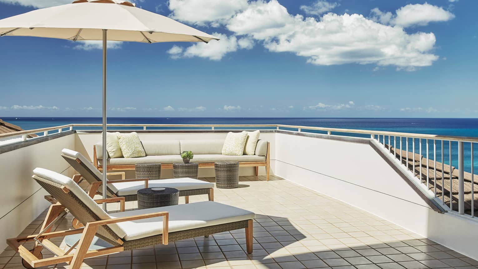 White cushioned wicker patio furniture, umbrella on rooftop balcony