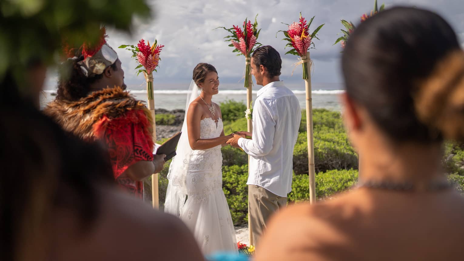 Guests watch as bride and groom hold hands at outdoor wedding ceremony 