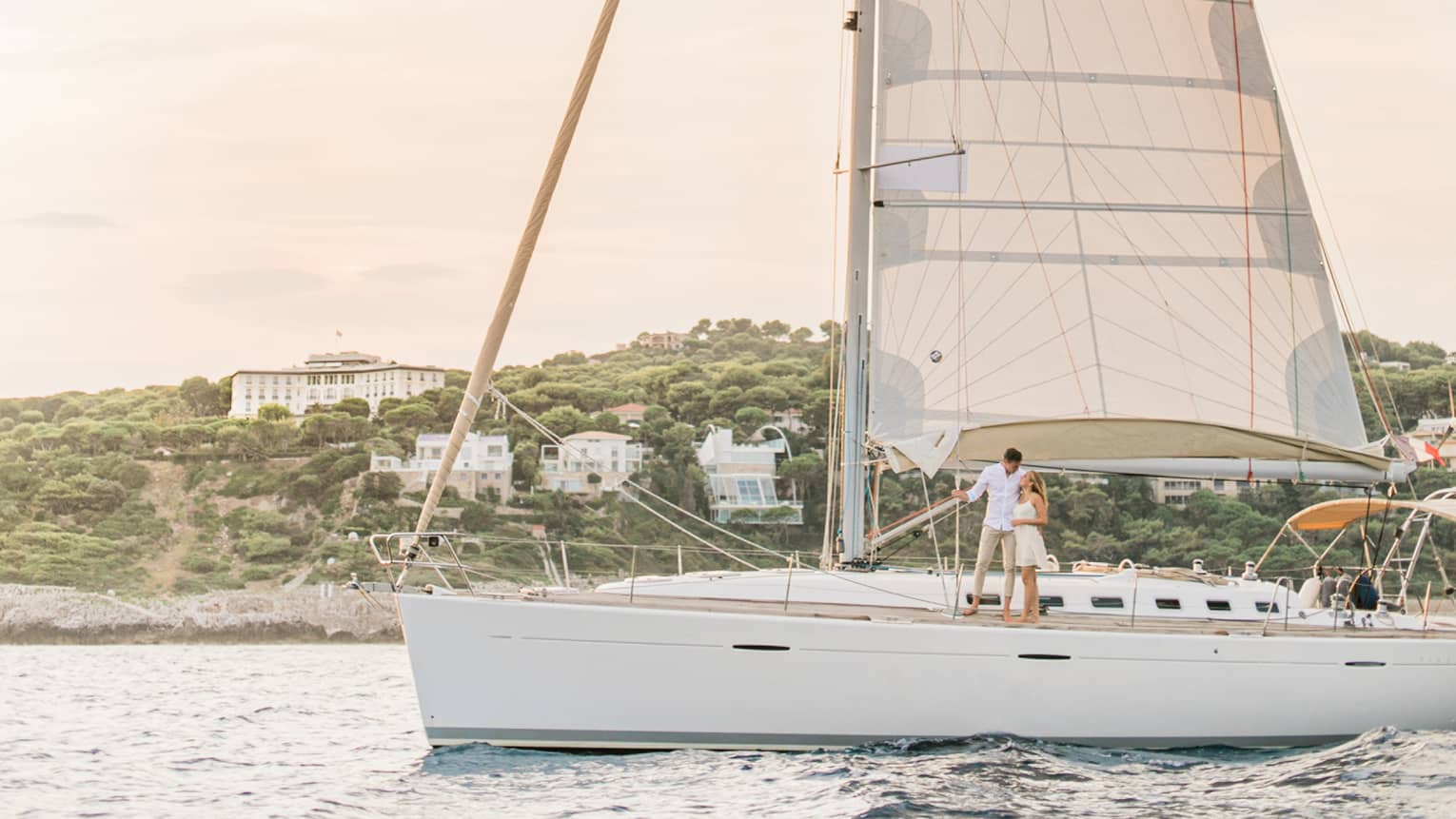 White sailboat on water in front of island with white buildings