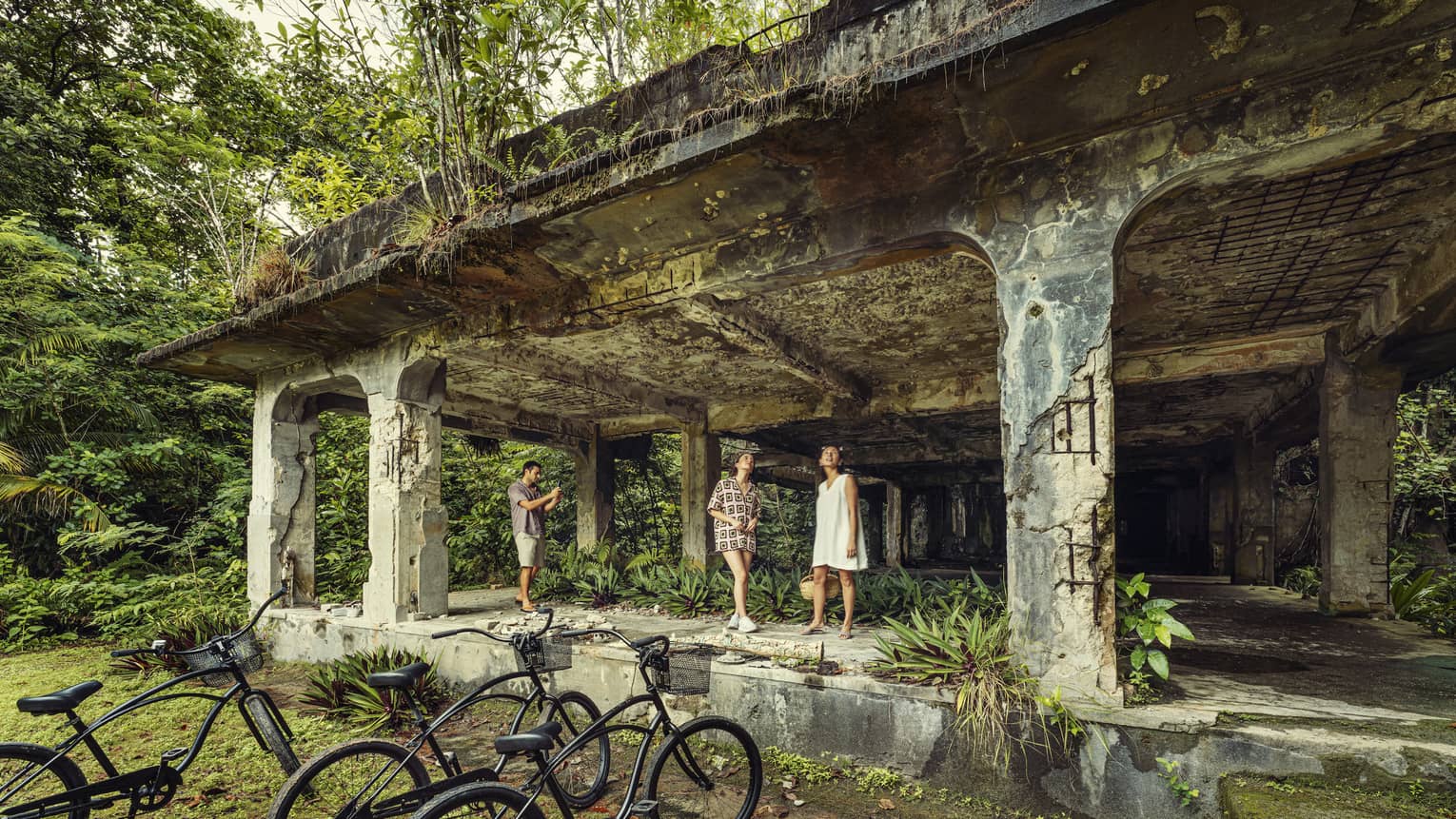 Two women and a man explore the Peleliu Island WWII relics, bicycles in foreground