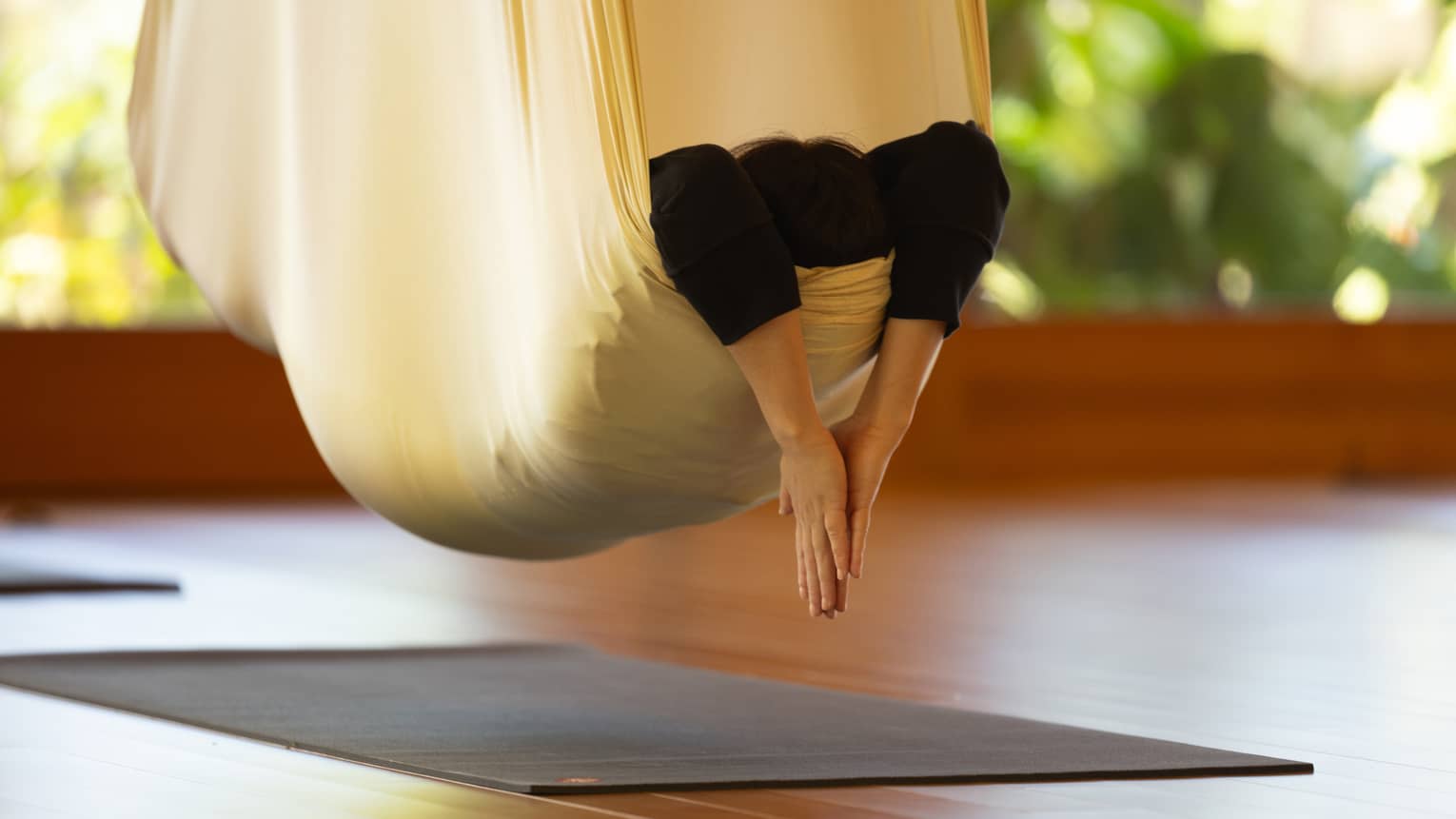 A person practicing hanging yoga.