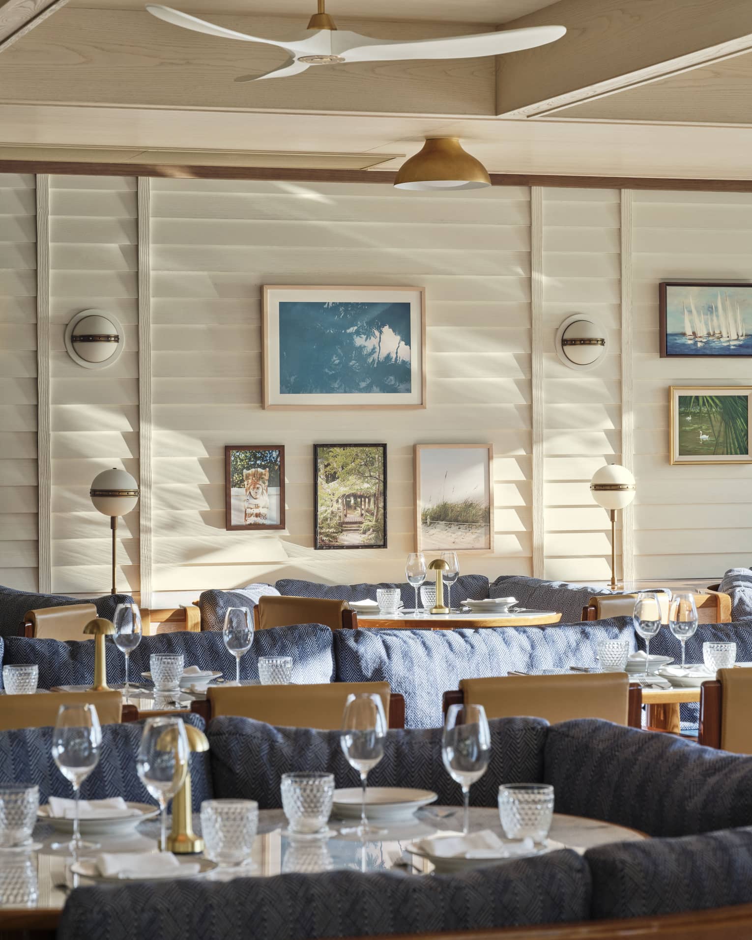 The interior of a restaurant with large booths with blue cushions and art on a wall.
