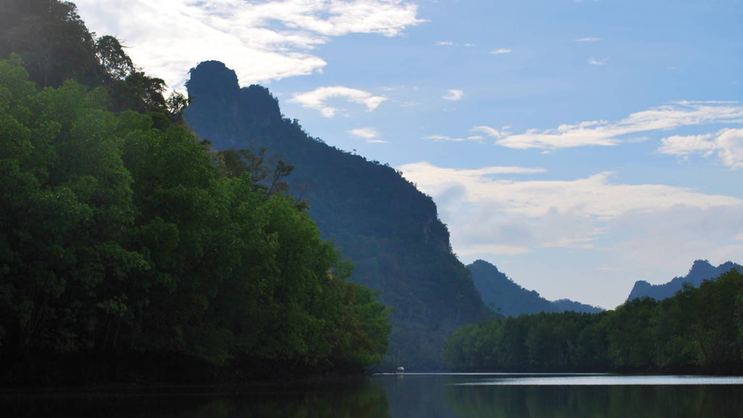 Large, lush green mountains tower over river
