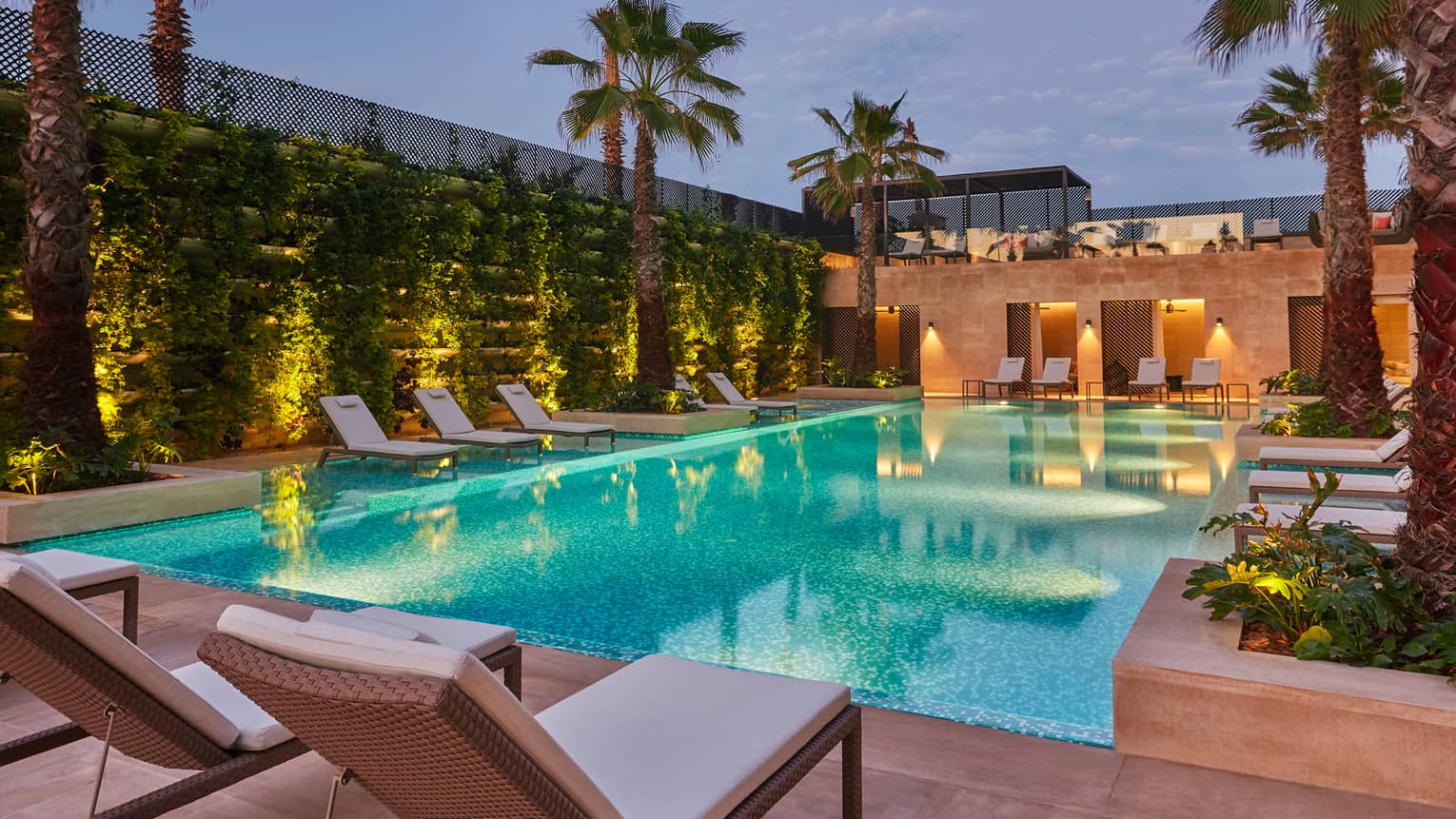 White lounge chairs around outdoor swimming pool, tropical plants 