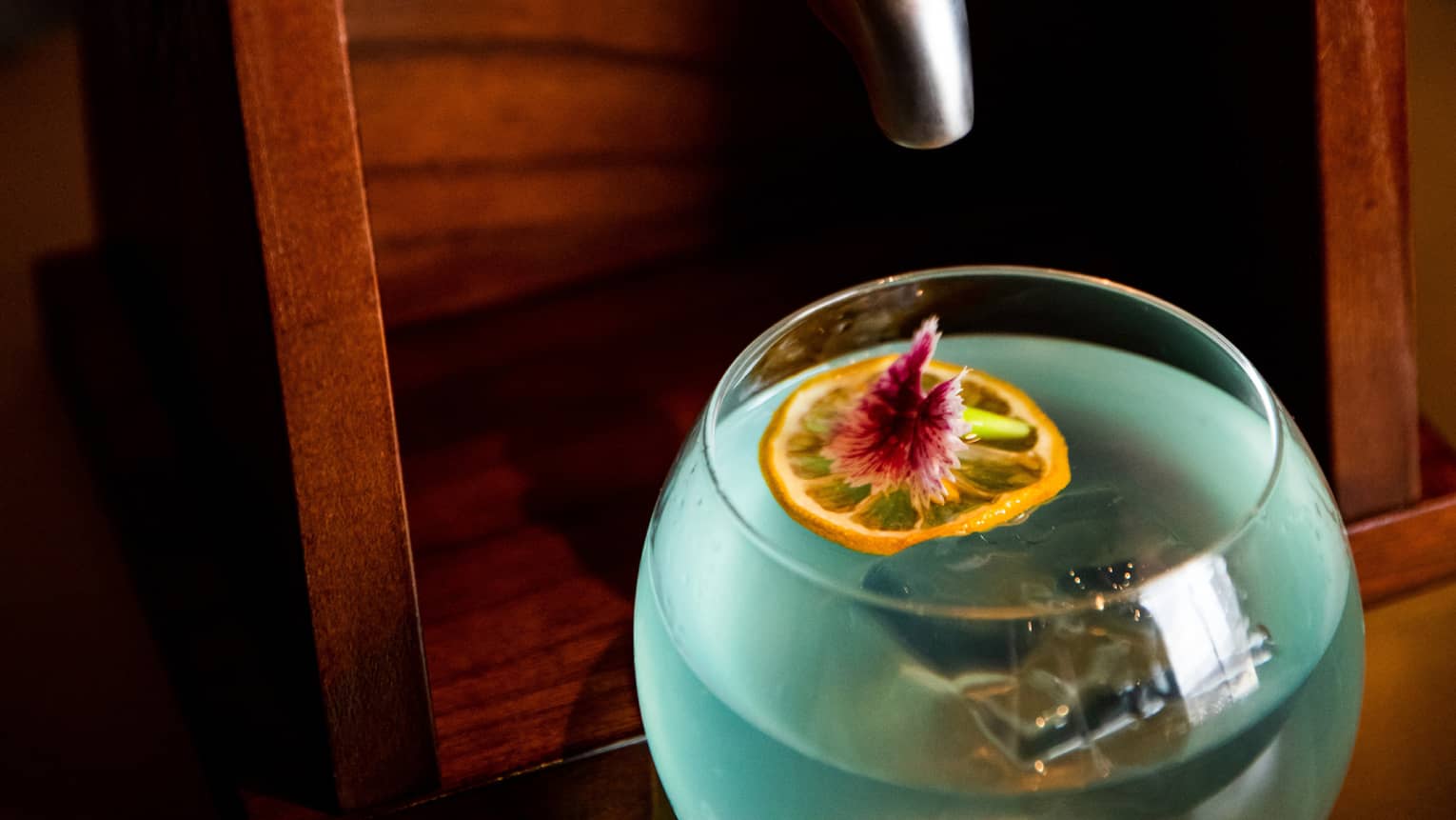 A blue cocktail with a ship in a bottle above it.